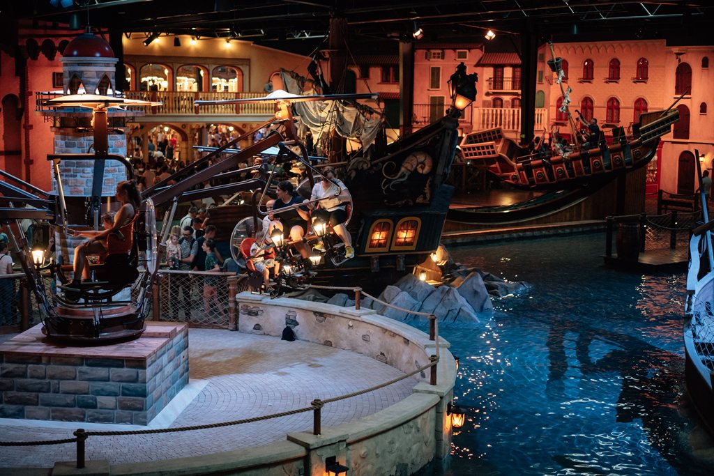 View of the Mandoria attractions with scenery reminiscent of Venice – water, tenement houses on the canals, ships and boats stylized as old ones, a carousel.