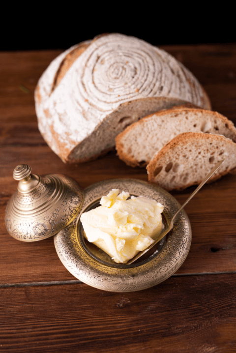 stół, masło w maselnicy, obok leży pieczywo