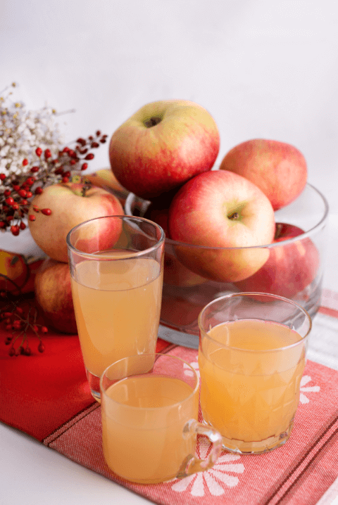 trzy szklanki z sokiem w tle naczynie z jabłkami